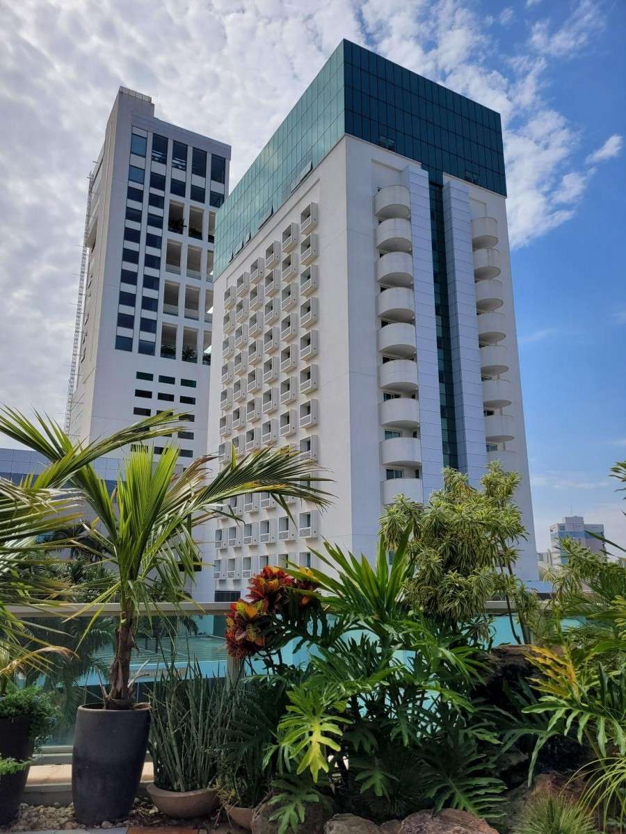 Vista externa dos prédios do Mercure Uberlândia, com duas torres altas, cercadas por vegetação.